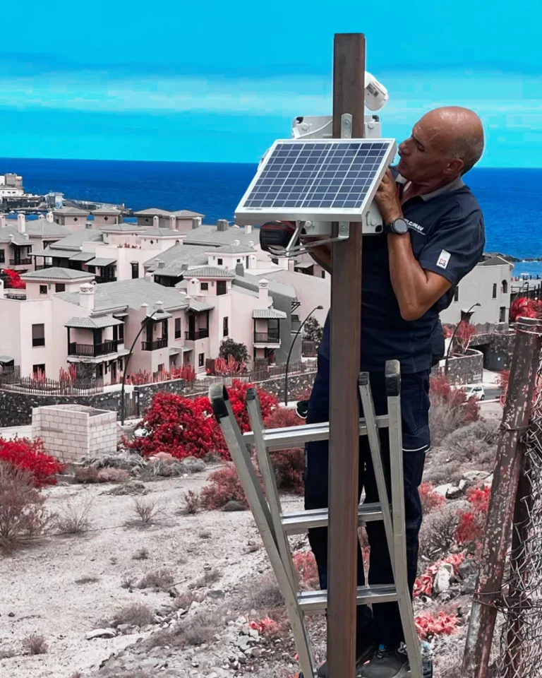 Técnico de TELCONAV instalando una cámara de seguridad autónoma con panel solar en exteriores.